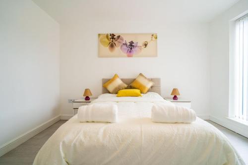 a white bedroom with a large white bed with yellow pillows at Mulberry Garden in Coventry
