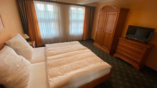 a hotel room with a bed and a television at Altstadt-Refugium - Schlossblick, Sauna, Parkplatz, Innenstadt, Wow Sky Sport BL in Wernigerode