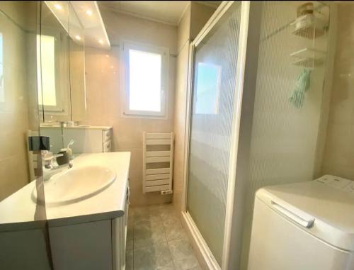 une salle de bain blanche avec un lavabo et une douche dans l'établissement Clair Matin T3, à Six-Fours-les-Plages