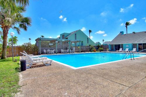 a swimming pool with chairs and a house at Puente Vista 106 in Padre Island