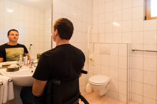a man standing in a bathroom looking at himself in the mirror at Haus Renate in Kaunertal