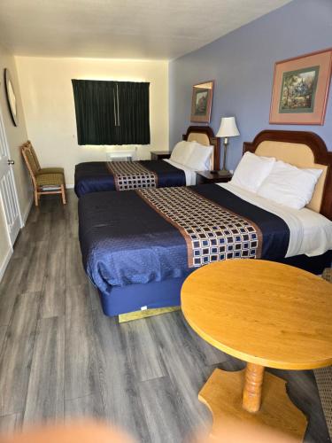 a hotel room with two beds and a table at Rodeway Inn & Suites Blythe I-10 in Blythe