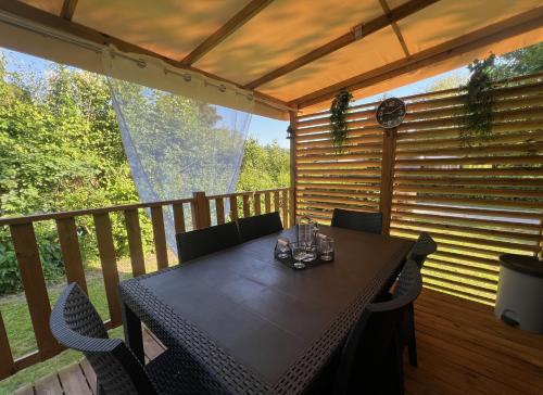 une terrasse couverte en bois avec une table et des chaises. dans l'établissement Ivry calme détente piscine sport famille by Vayny, à Ivry-la-Bataille