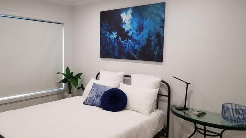 a white bedroom with a bed and a glass table at At Home Apartments in Sale