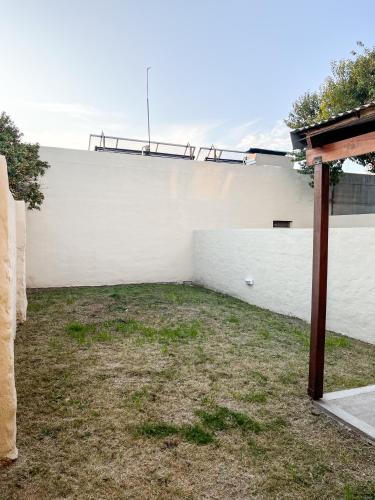 a backyard with a white wall and a fence at Cuatro Estaciones in General Pico