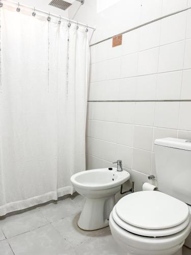 a white bathroom with a toilet and a shower at Cuatro Estaciones in General Pico