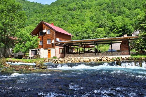 a house next to a river in front of a house at Domacinstvo na kraju svijeta in Šipovo