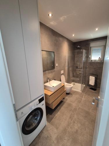 a bathroom with a washer and a washing machine at Adriatic Wave Residence in Brodarica