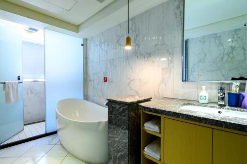 a bathroom with a tub and a sink and a mirror at Olah Poshtel Taichung Wenxin in Taichung
