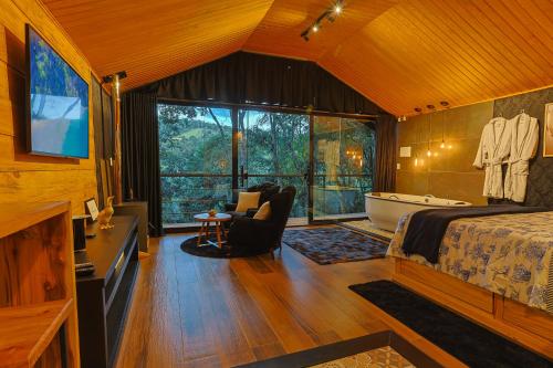 a bedroom with a bed and a tub and a television at Requinte dos Pinhais Chalé in Santo Antônio do Pinhal