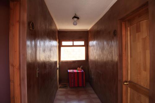 a hallway with a door and a red suitcase at Sol del Desierto in Chíuchíu