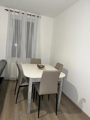 une salle à manger avec une table et des chaises blanches dans l'établissement Appartement Le Havre, au Havre