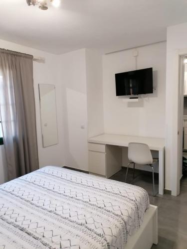 a white bedroom with a bed and a desk at Appartamento Puerta del Sol in Caleta De Fuste