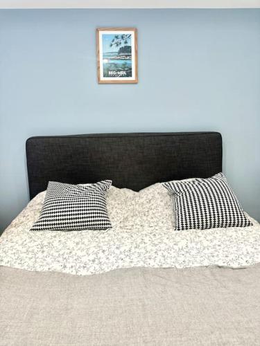 a bed with a black head board and two pillows at Maison de vacances Audierne centre avec terrasse proche des plages in Audierne