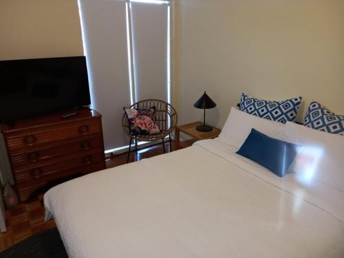 a bedroom with a white bed and a television at At Home Apartments in Sale