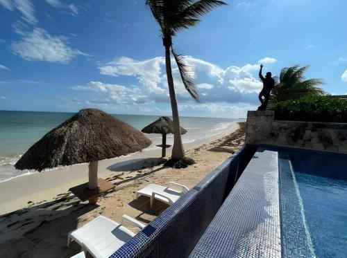 una piscina junto a una playa con una estatua en Palma Real By Andiani Travel, en Puerto Morelos