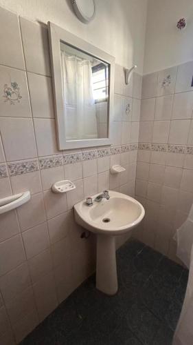 a white bathroom with a sink and a mirror at 760 B Apartamentos in Alta Gracia