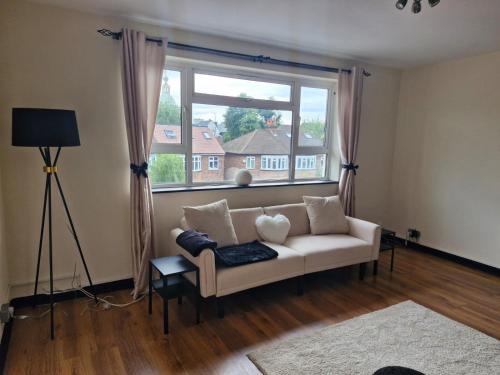 a living room with a couch and a large window at Elegant & Spacious 2-Bedroom Apartment in Wimbledon in London
