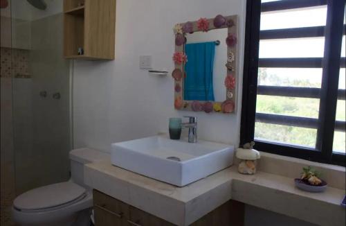a bathroom with a sink and a toilet and a mirror at Casa Mar in Chelem