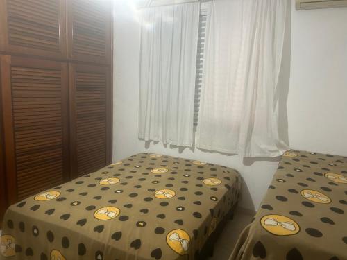 a bedroom with two twin beds and a window at ED. ITAMARATI. in Praia Grande