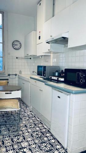 une cuisine avec des placards blancs et une horloge murale dans l'établissement Appartement hausmanien centre Montpellier, à Montpellier