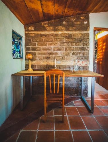 a wooden table with a chair and a brick wall at Lush Atitlán in San Marcos La Laguna