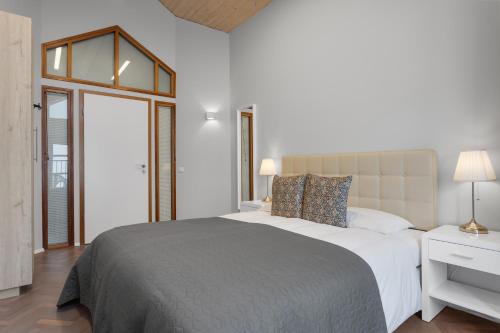 a white bedroom with a large bed and a window at Thorsplan Luxury Apartment in Hafnarfjördur