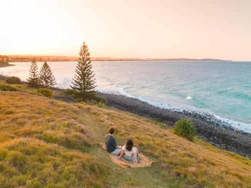 a man and woman sitting on a blanket looking at the ocean at BIG4 Tasman Holiday Parks - Ballina in Lennox Head