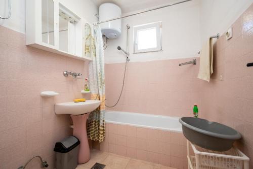 a pink bathroom with a sink and a bath tub at Apartment Vidalici 6519f in Kustići