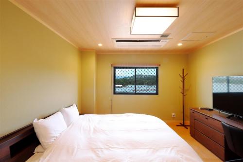 a bedroom with a bed and a flat screen tv at Kaigaku Onsen Resort Shirahama in Shirahama