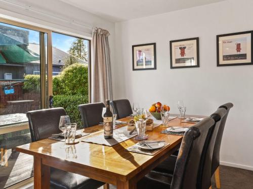 a dining room table with chairs and a large window at Hepburn Haven Retreat in Hanmer Springs