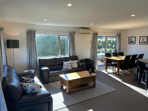 a living room with a leather couch and a table at Hepburn Haven Retreat in Hanmer Springs