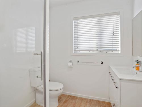 a white bathroom with a toilet and a sink at Hepburn Haven Retreat in Hanmer Springs