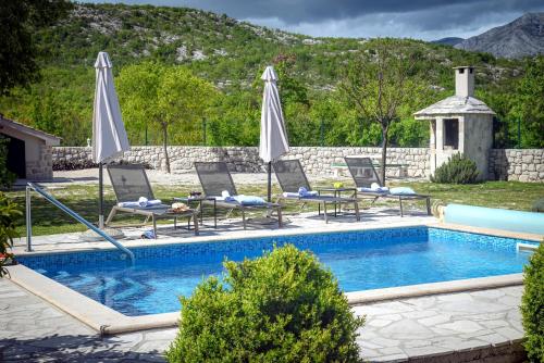a swimming pool with lounge chairs and umbrellas at Family friendly house with a swimming pool Duge Njive, Zagora - 22311 in Vrgorac