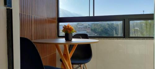 a table with chairs and a vase with flowers on it at Hospedagem Encantos da Serra in Itatiaia