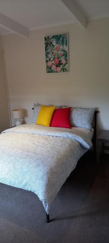 a bedroom with a bed with colorful pillows on it at At Home Apartments in Sale