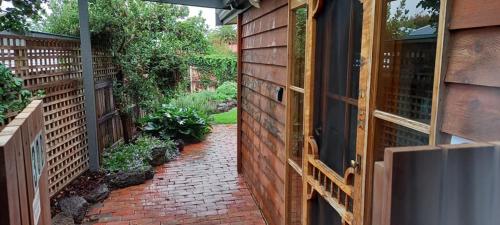 a brick walkway leading into a backyard with a fence at At Home Apartments in Sale