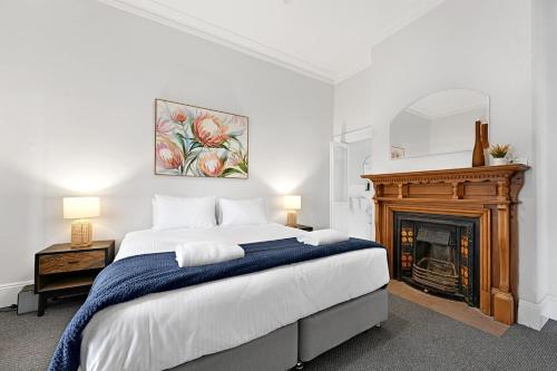 una camera con un grande letto e un camino di Dunkley House - Large CBD Heritage Home, Sleeps 10 a Bathurst