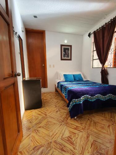 a bedroom with a bed and a wooden floor at Casa Morenita mía in San Cristóbal de Las Casas