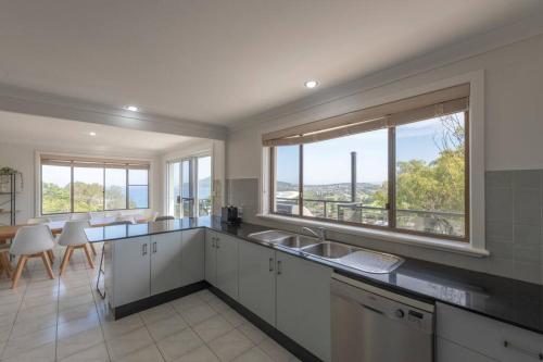 a kitchen with white cabinets and a large window at Dreamtime Beach Retreat - 4 Bedroom with Ocean View in Forster