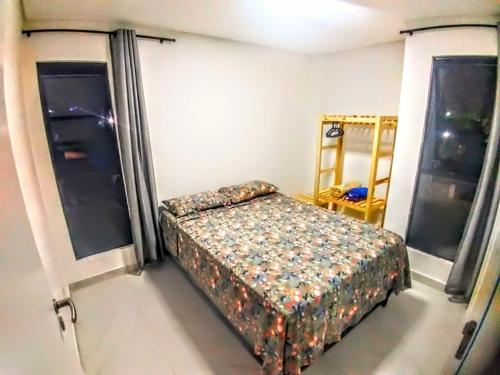 a small bedroom with a bed and two windows at Flat 104 - Na Rua das Piscinas Naturais no Centro de Porto de Galinhas in Porto De Galinhas