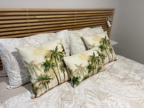ein Bett mit vier Kissen mit Palmen darauf in der Unterkunft Sussex Gem - Cozy apartment in the heart of Sussex in Sussex inlet