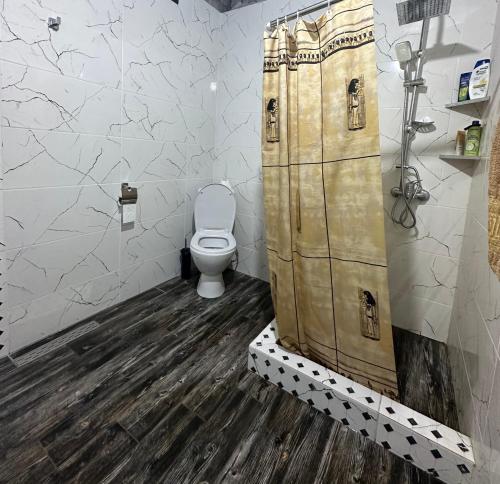 a bathroom with a toilet and a wooden shower stall at Racha - ABA in Ambrolauri