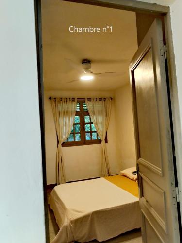 a small bedroom with a bed and a window at Haut de villa créole, vue sur mer in Baillif