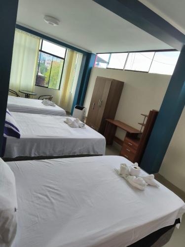 a room with two beds and a table and windows at HOTEL VIP 46 SSQS in Bagua Grande