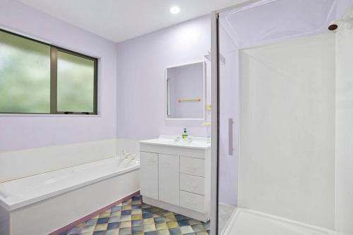 a white bathroom with a tub and a sink and a shower at Family Hideaway in Hanmer Springs