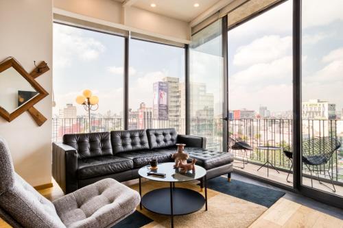 a living room with a black leather couch and a large window at FORMA By Mr W in Mexico City