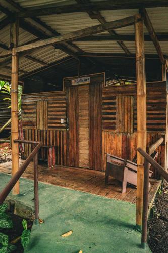 a wooden porch of a house with a sign on it at Flutterby House Hostel in Uvita