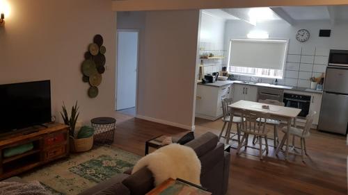 a living room with a couch and a table and a kitchen at At Home Apartments in Sale