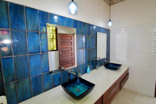 a blue tiled bathroom with a sink and a mirror at Wild Serenity's Beach Villa in Castries